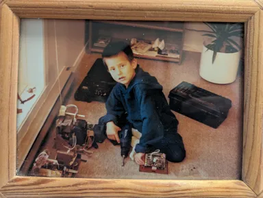 A picture of me at a young age holding a drill while disassembling part of a CRT television